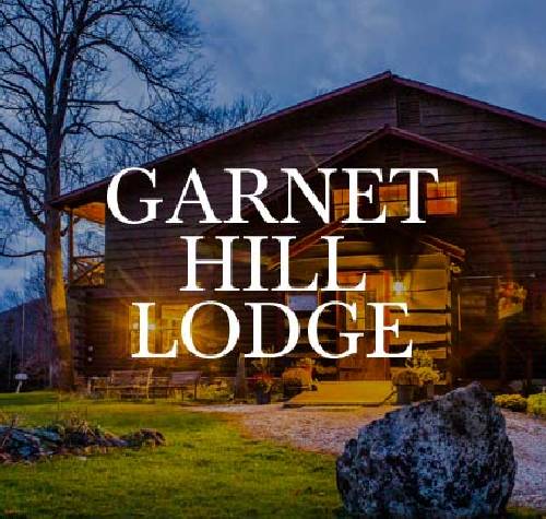 Garnet Hill Lodge logo with one of their cabins in the background.