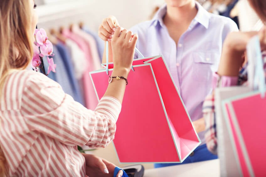 Closeup mid section of female customer receiving shopping bags in boutique