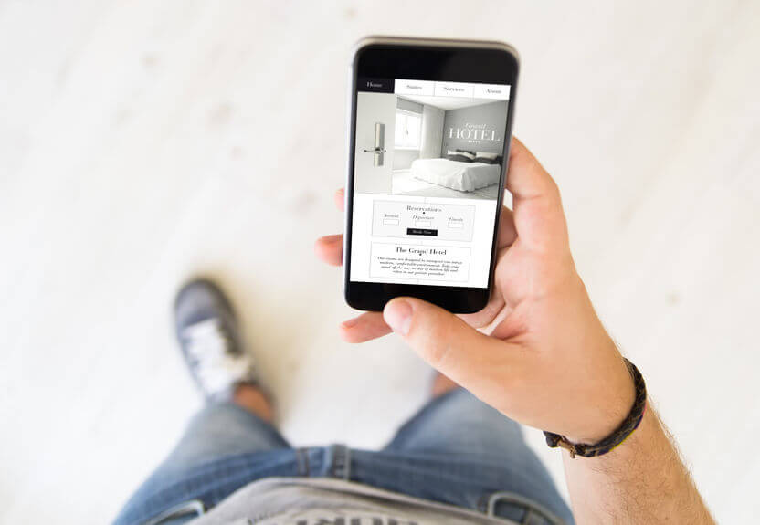 close up of male hand booking a room on smart phone