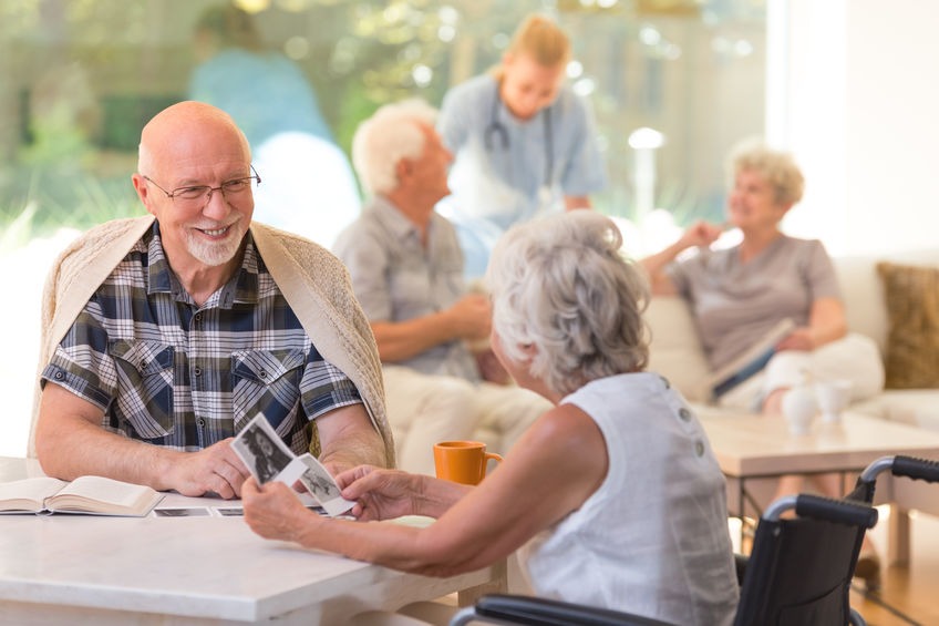 Married couple of elders sitting together and watching old photos at senior living community