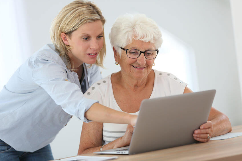 Older child with elderly woman using laptop computer