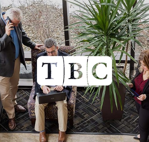 TBC logo with people working in the background.