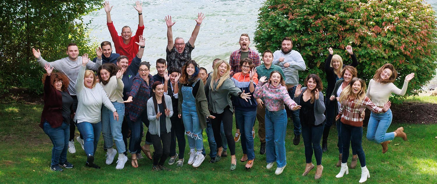 Employees of Mannix Marketing jumping and posing for a picture at their company retreat.